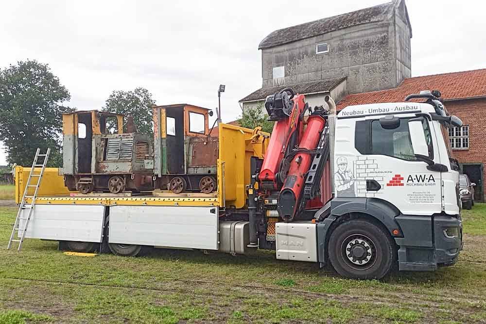 Ein Lastwagen mit einem Zug auf der Ladefläche steht auf einem Feld.