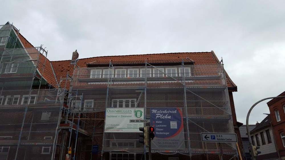 Gebäude im Umbau, rotes Ziegeldach, Baugerüst, Schild mit der Aufschrift „Wiesmoor’s Mühle“, bewölkter Himmel.