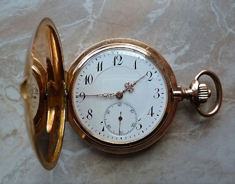Geöffnete goldene Taschenuhr, weißes Zifferblatt mit schwarzen Ziffern und kleiner Sekunde sichtbar.