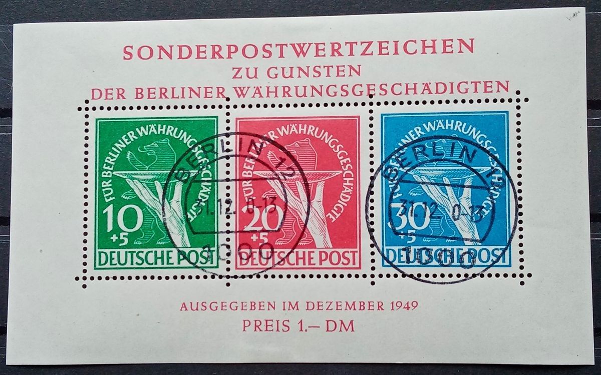 Drei deutsche Briefmarken auf einem Umschlag, grün, rot und blau, mit schwarzen Entwertungsstempeln.