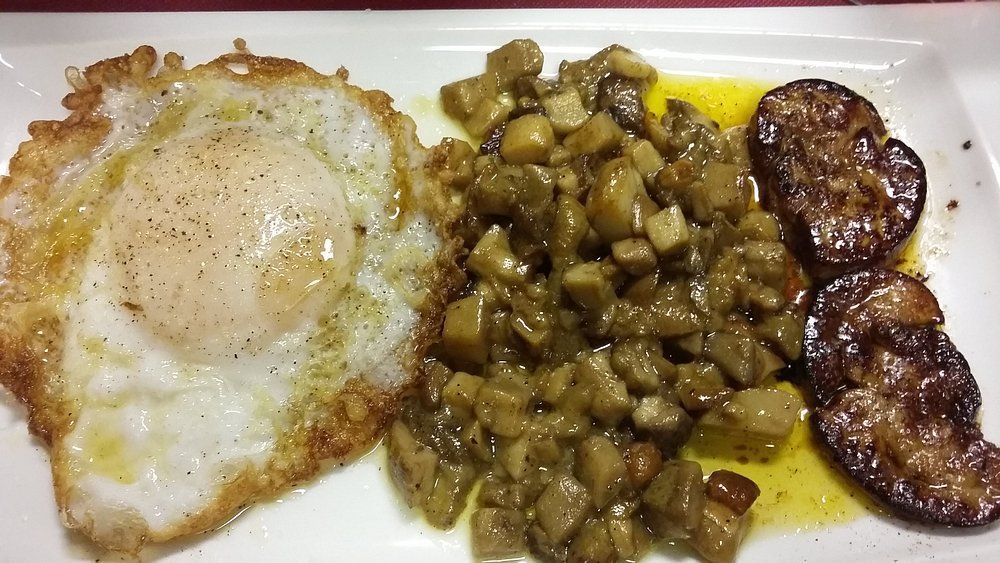 Huevo frito, verduras salteadas en cubitos y berenjena a la parrilla en un plato blanco.