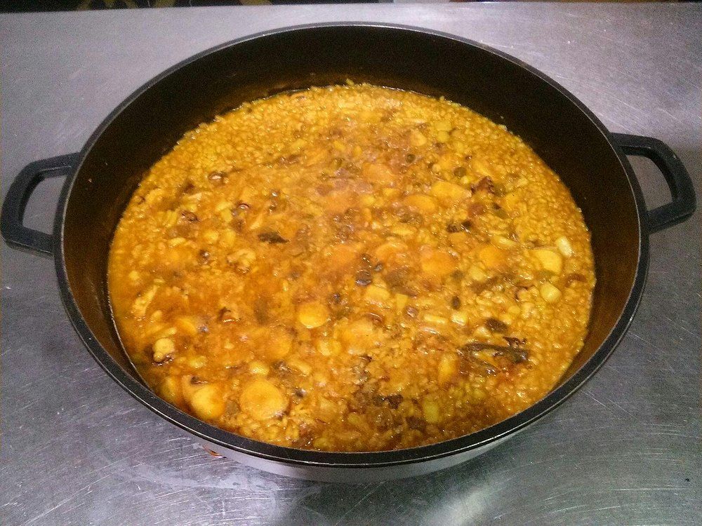 Guisar en una olla de hierro fundido de color negro sobre una superficie metálica.