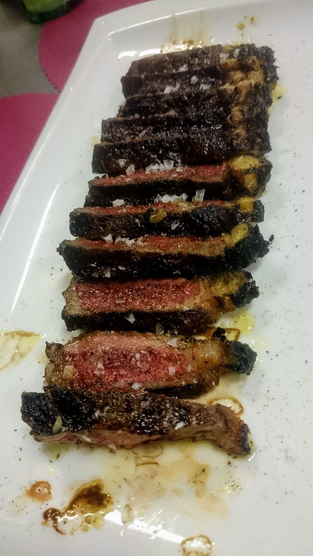 Filete cortado en rodajas, a medio cocinar, en un plato rectangular blanco, con sal y aceite espolvoreados.