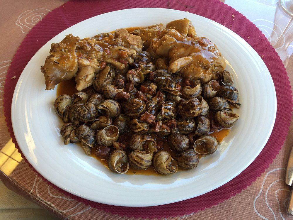 Plato de comida con caracoles y carne en salsa marrón.