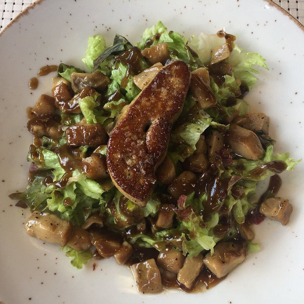 Ensalada con foie gras sellado, verduras mixtas y champiñones rociados con salsa.