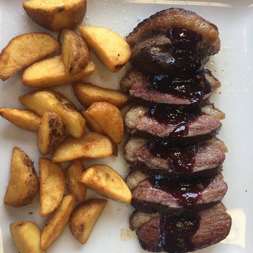 Pechuga de pato en rodajas con salsa de frutos rojos y patatas gajo.