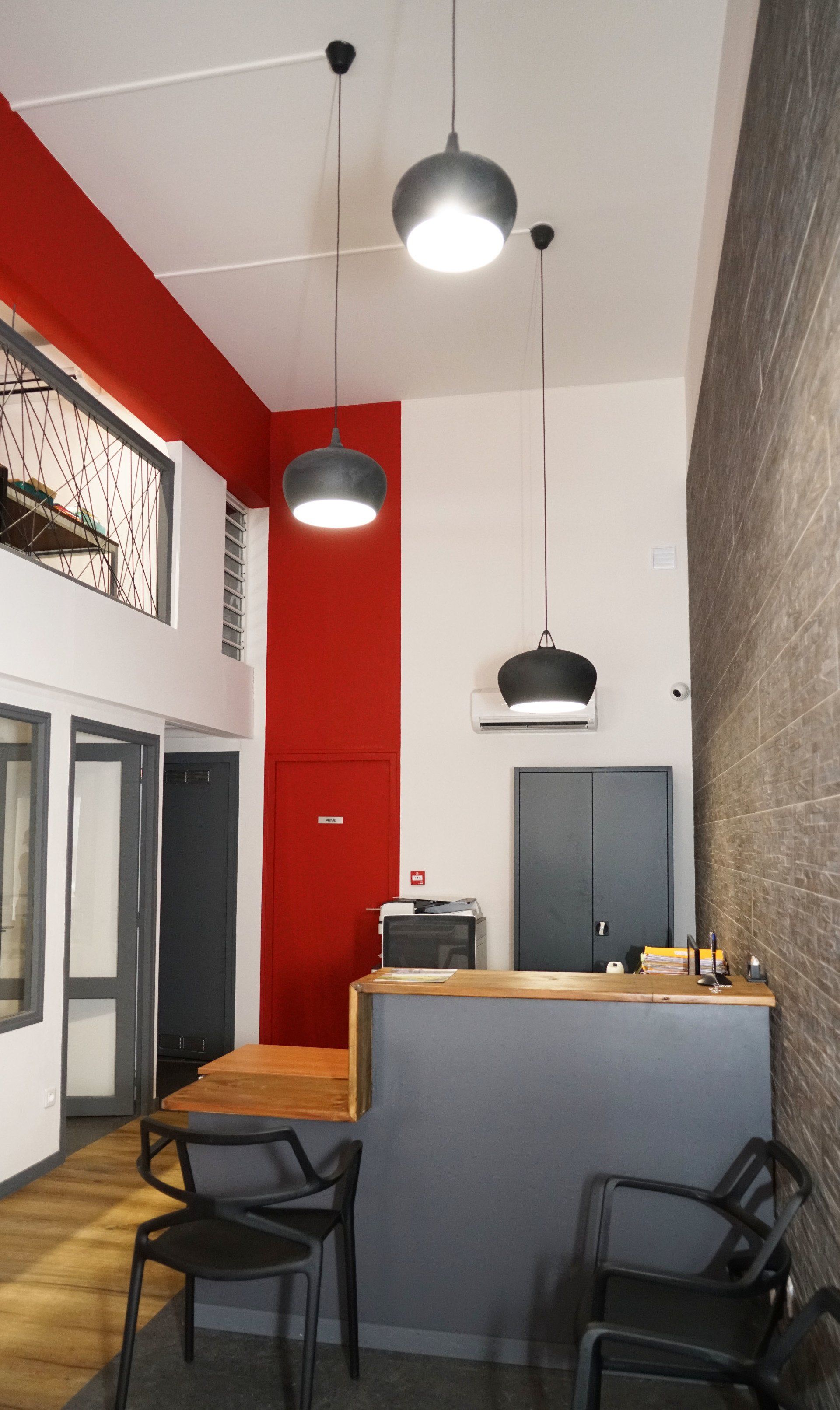 Une pièce rouge avec un bureau gris.