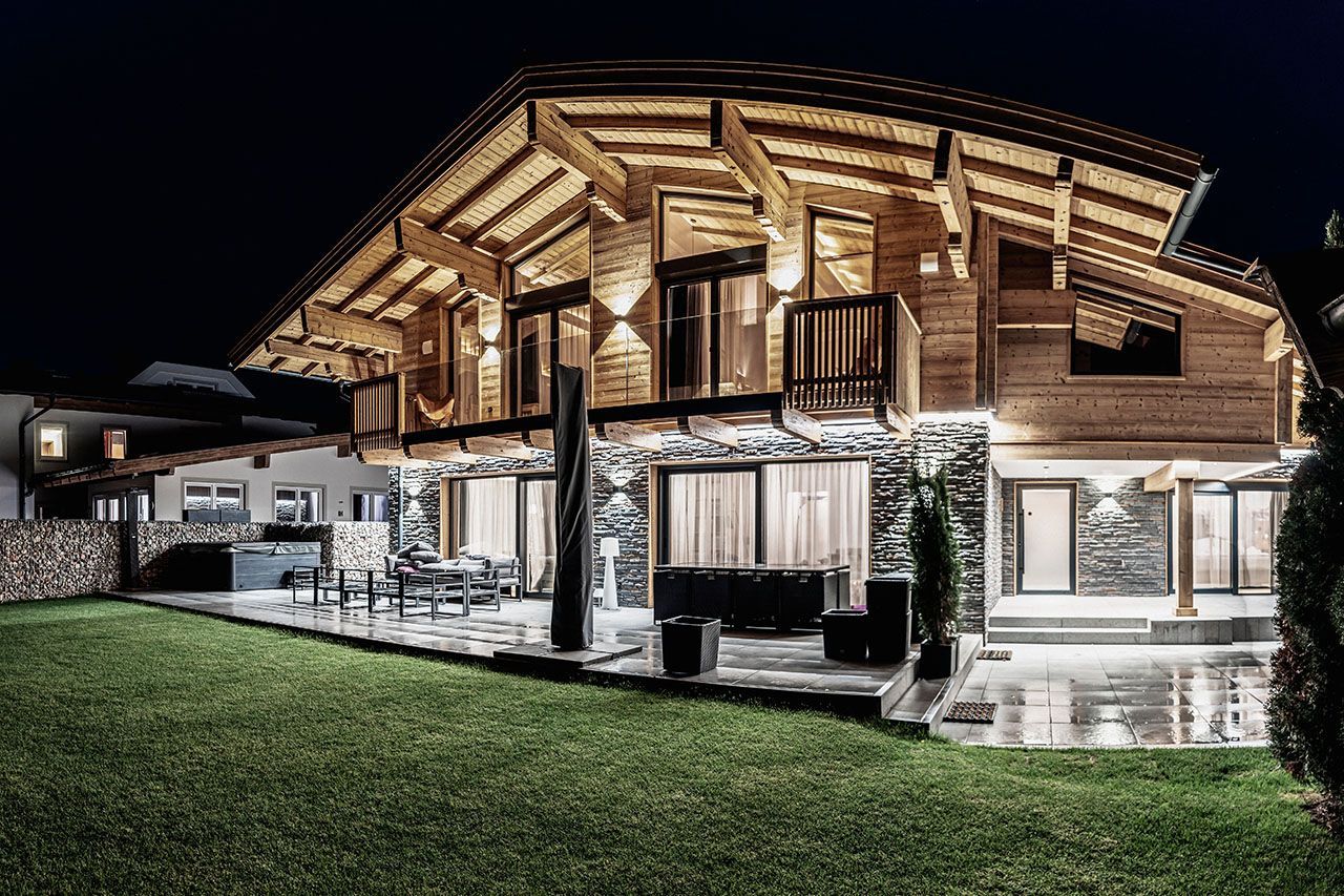 a large wooden house with a lot of windows is lit up at night .