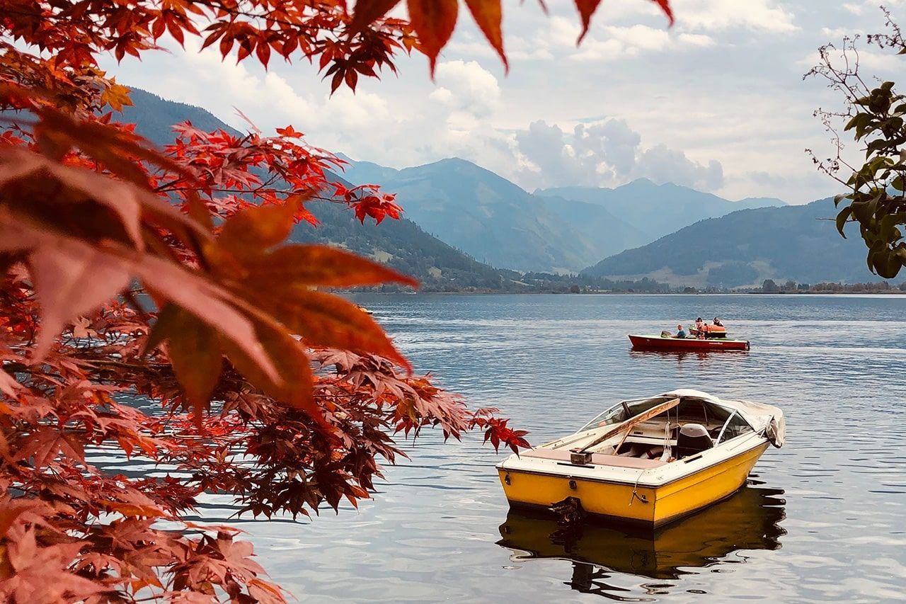 a yellow boat is floating on a lake with mountains in the background