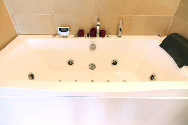 a white jacuzzi tub in a bathroom with a thermometer on the wall