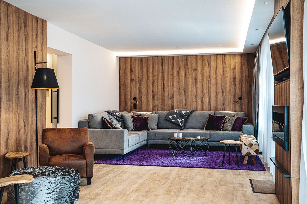 a living room with a large sectional couch and a purple rug .