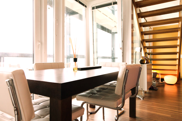 a dining room table with chairs and stairs in the background