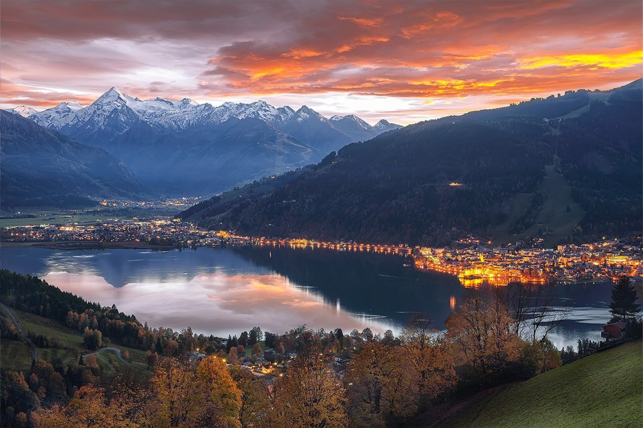 a city is surrounded by mountains and a lake at sunset