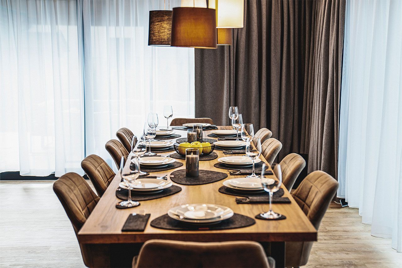 a long wooden dining table with plates and glasses on it in a room