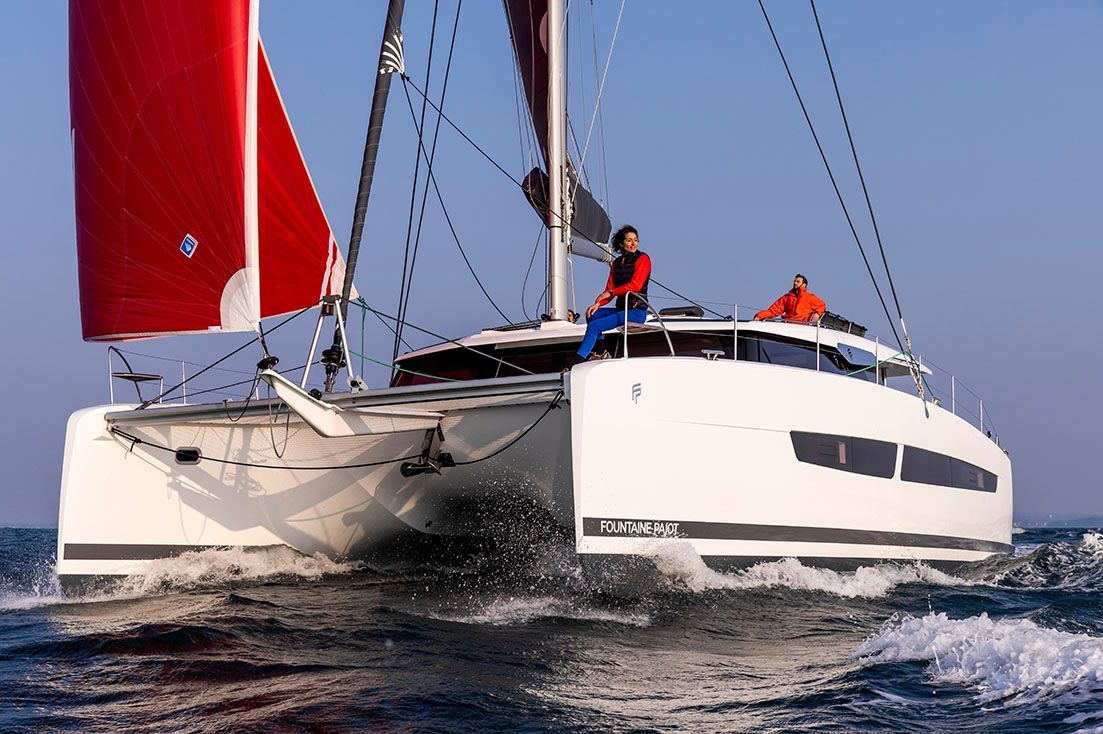 a sailboat with a red sail is floating on top of a body of water .