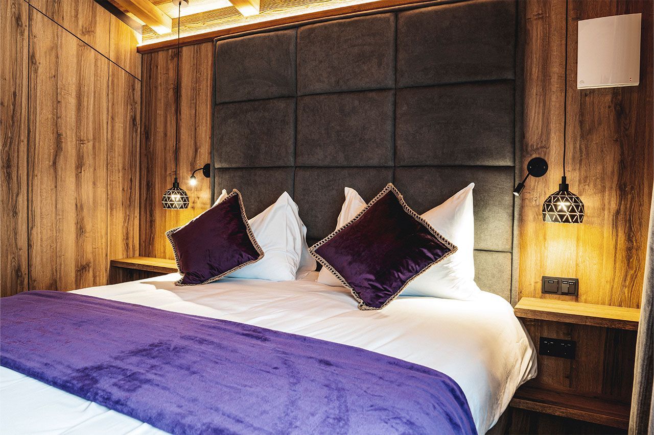 a bed with purple pillows and a purple blanket in a hotel room .