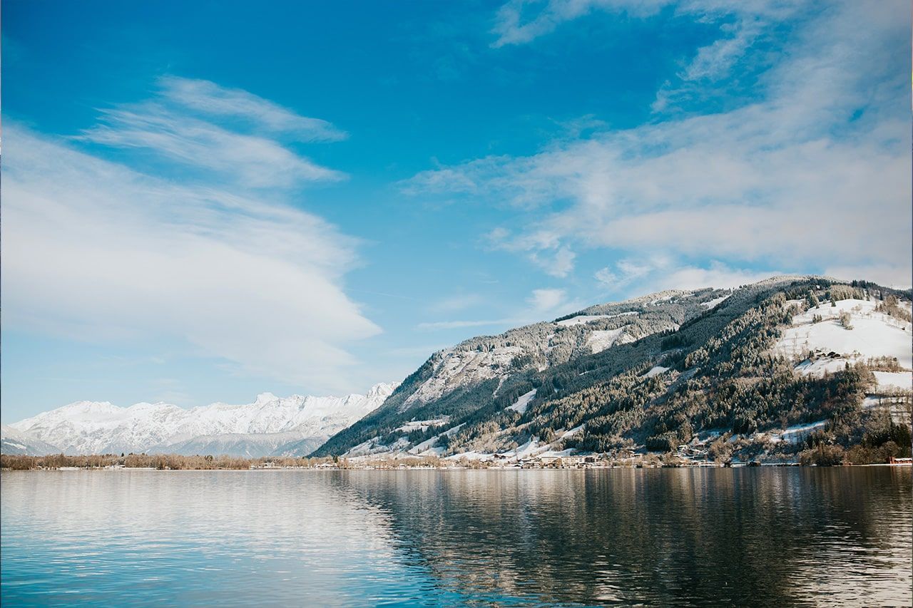 a lake surrounded by snow covered mountains on a sunny day