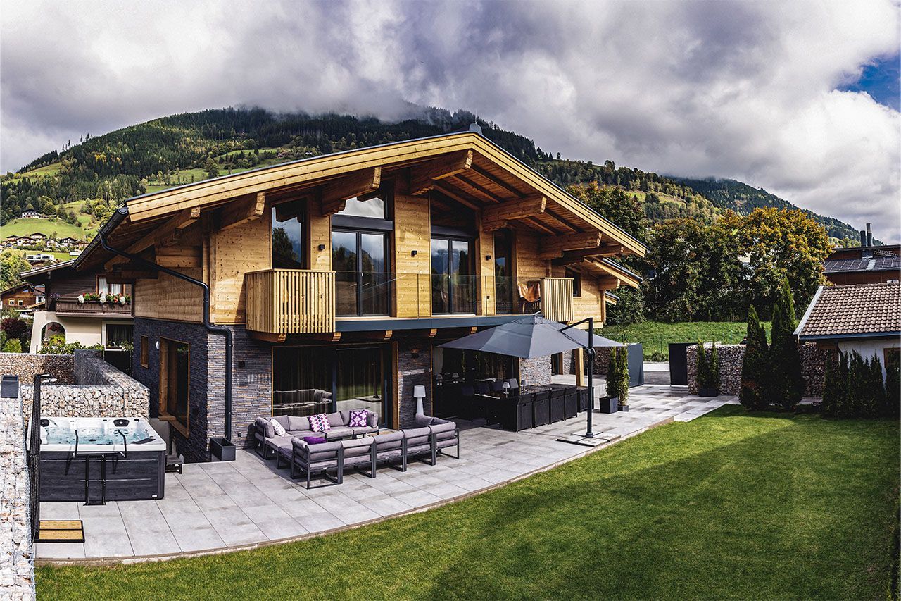 a large house with a hot tub in the backyard and mountains in the background .