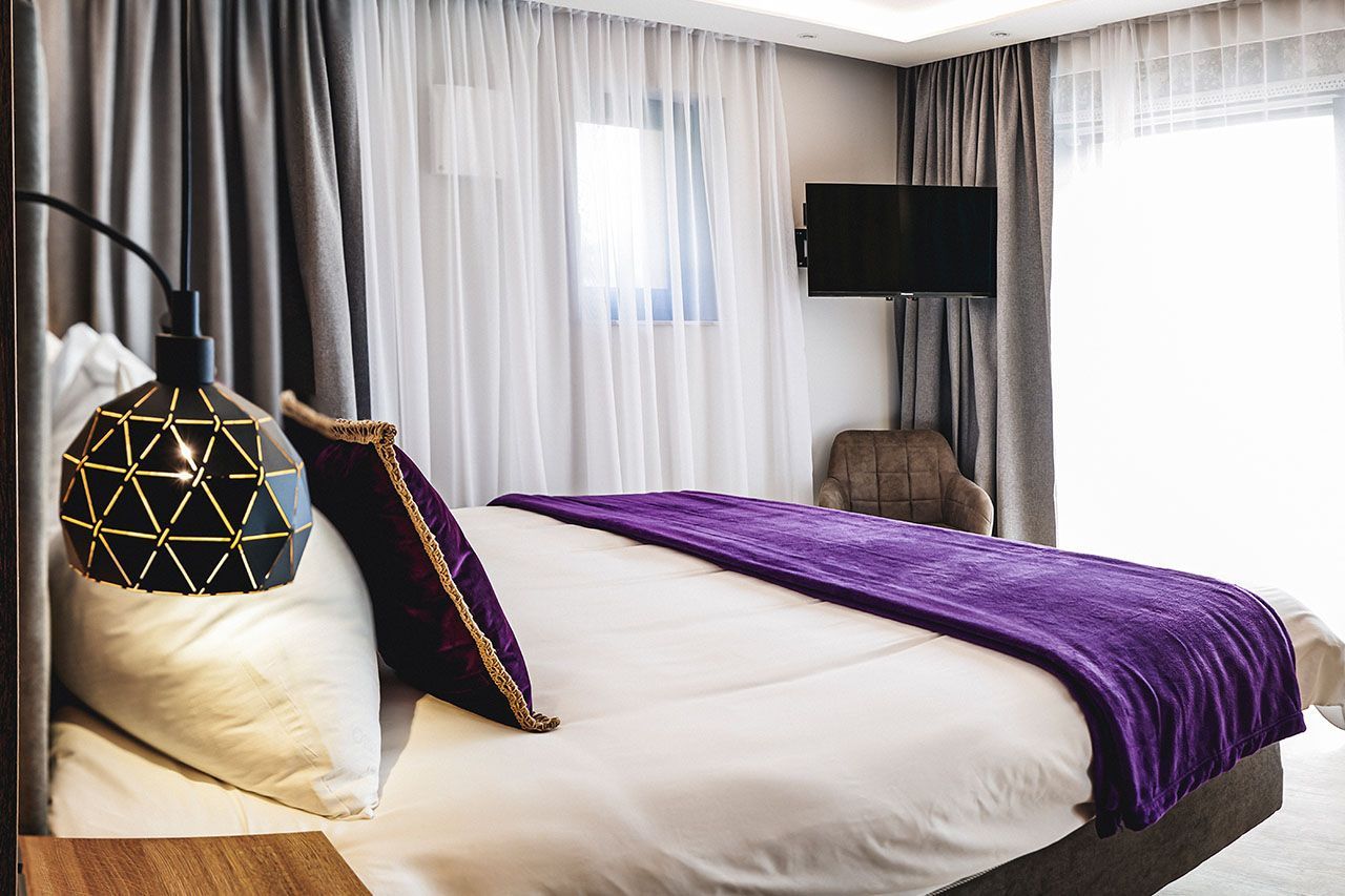 a hotel room with a king size bed and a purple blanket .