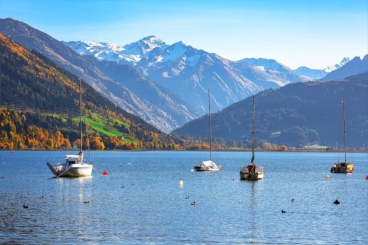 a group of sailboats are floating on a lake with mountains in the background