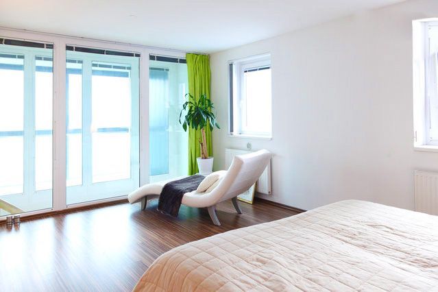 a bedroom with a bed , chair , plant and sliding glass doors