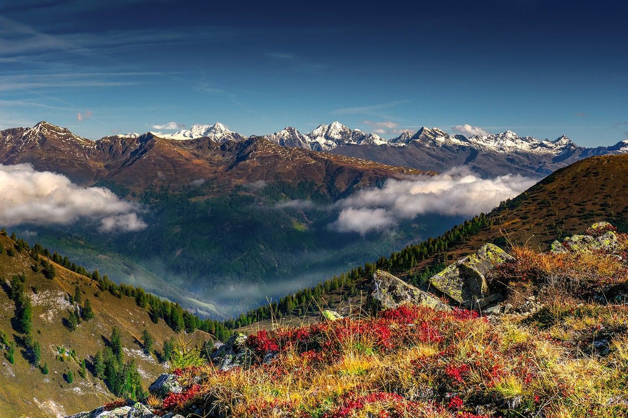 a view of a mountain valley with mountains in the background and clouds in the sky