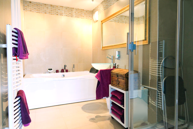 a bathroom with a bathtub , sink , mirror and towels