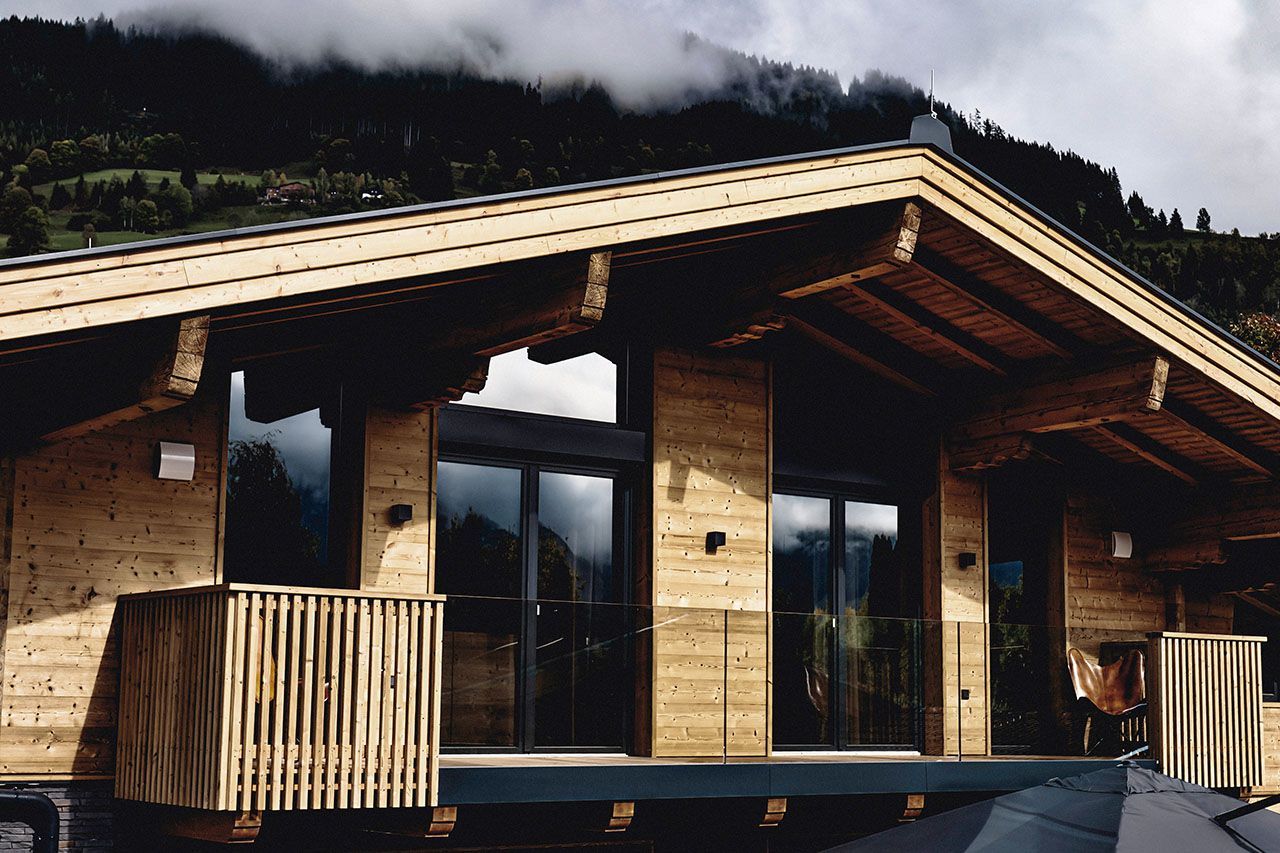 a large wooden house with mountains in the background