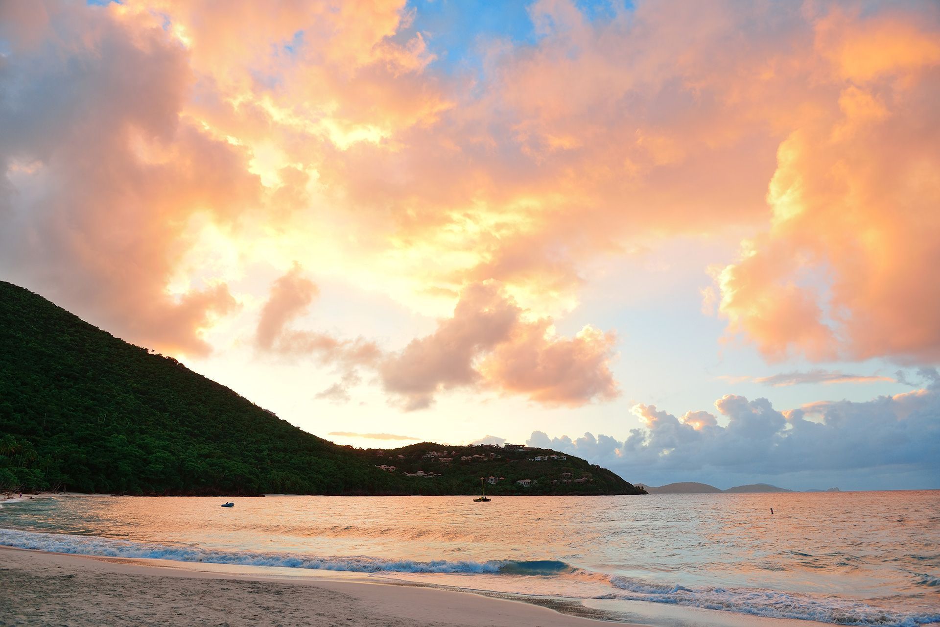 a sunset over a beach with a mountain in the background