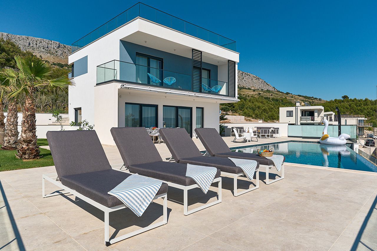 a row of lounge chairs are lined up in front of a modern house .