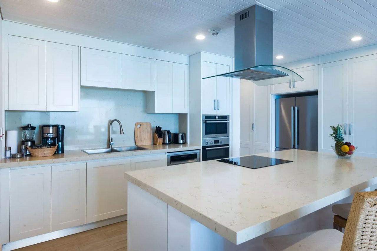 a kitchen with white cabinets, a stove top oven, a refrigerator, and a large island