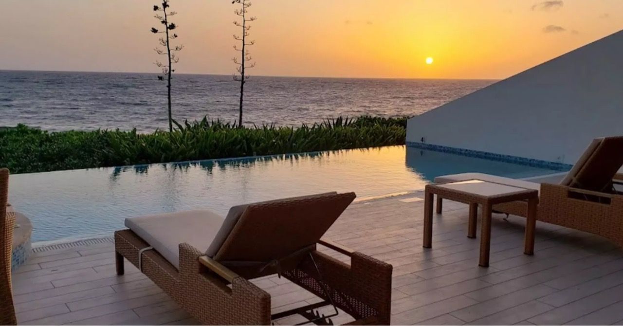 a swimming pool with a view of the ocean at sunset