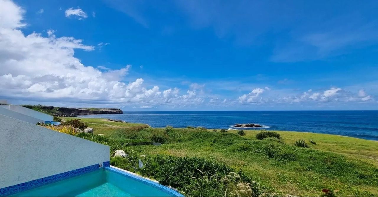 a view of the ocean from a balcony with a swimming pool in the foreground .