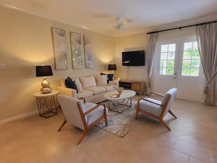 a living room with a couch , chairs , coffee table and television .