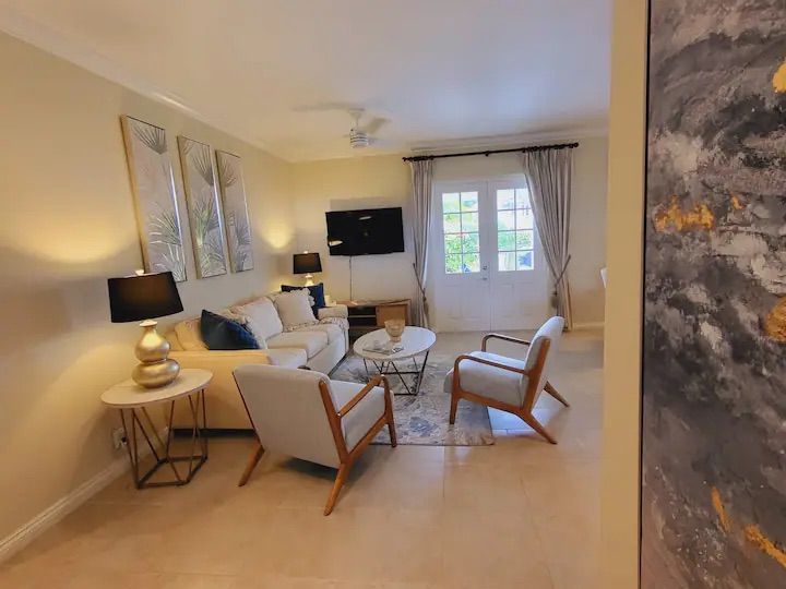 a living room with a couch , chairs , table and television .