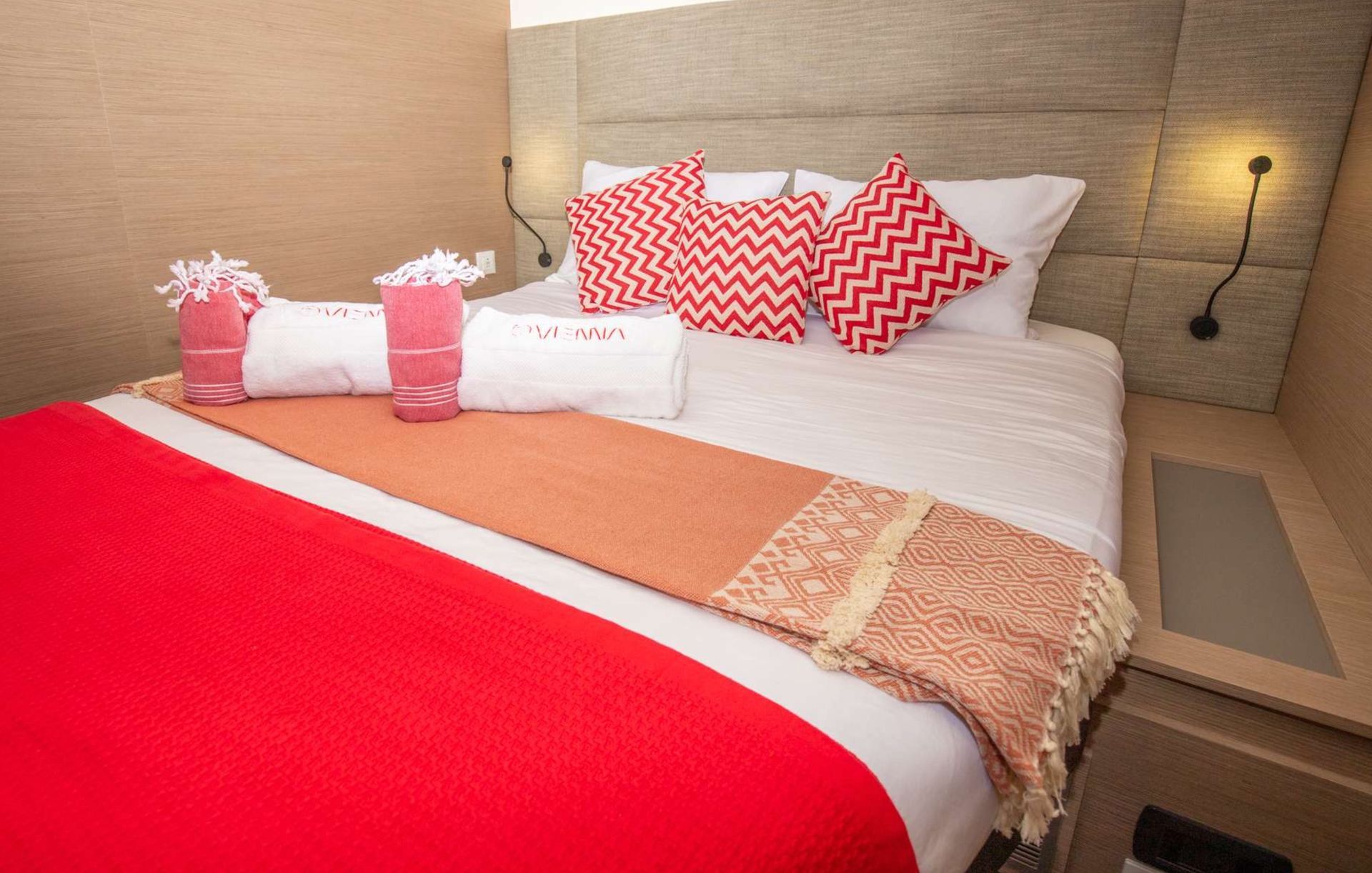 a bed with a red blanket and pillows in a hotel room