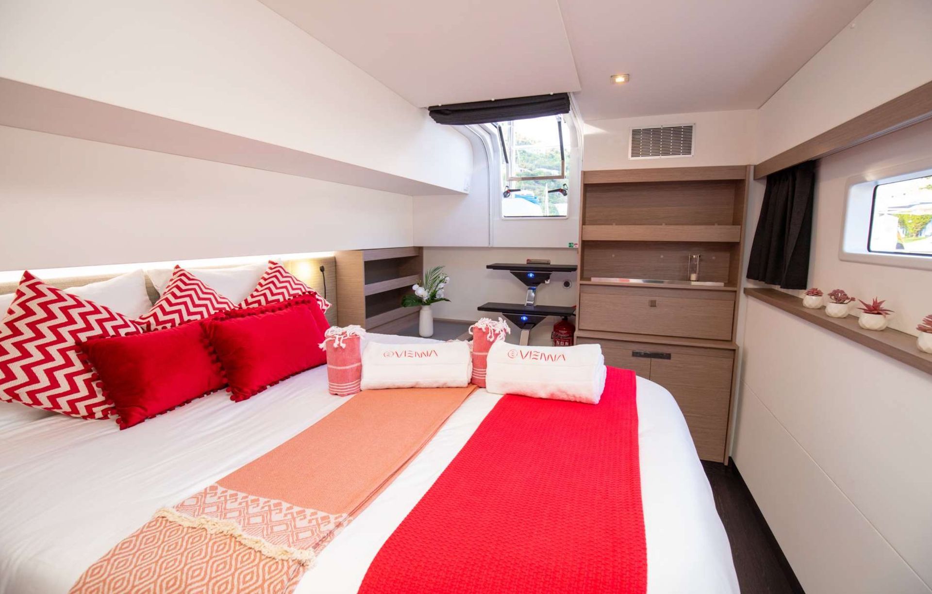 a bedroom on a boat with a large bed and red pillows