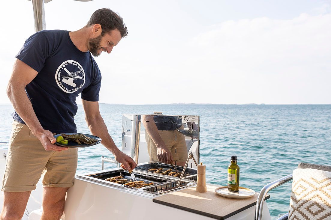 a man is cooking food on a boat in the ocean