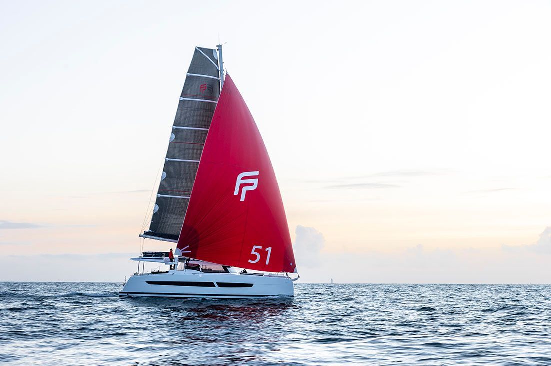 a sailboat with a red sail is floating on top of a body of water
