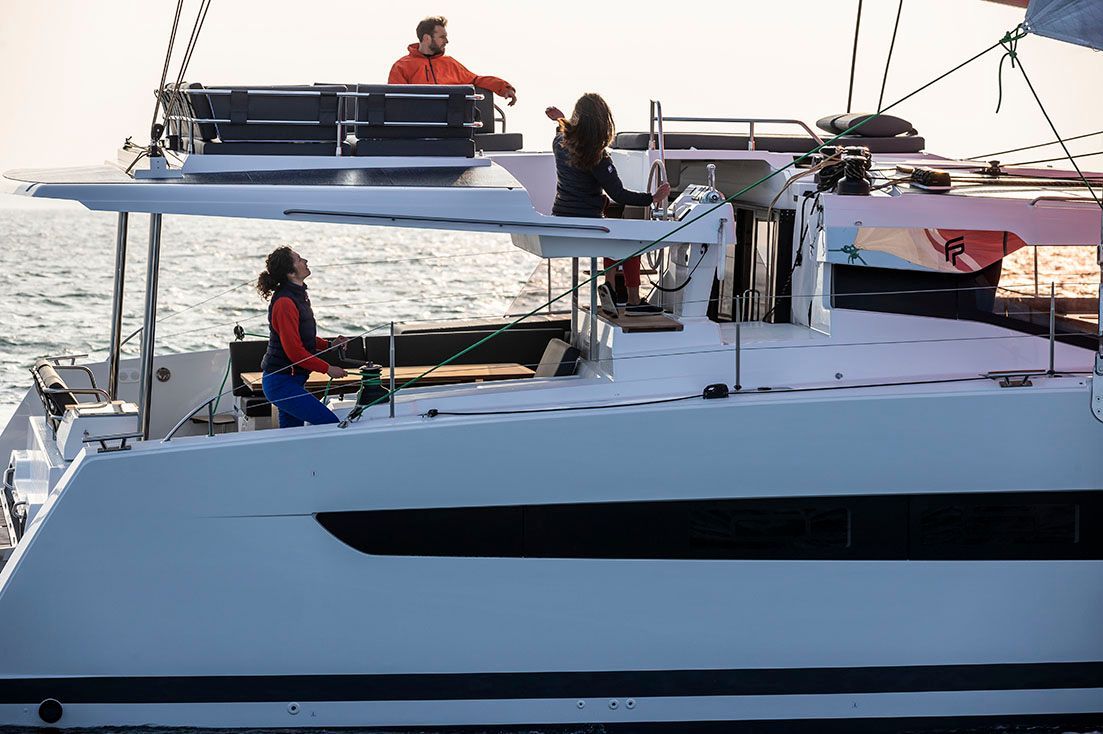 a group of people are fishing on a sailboat in the ocean .