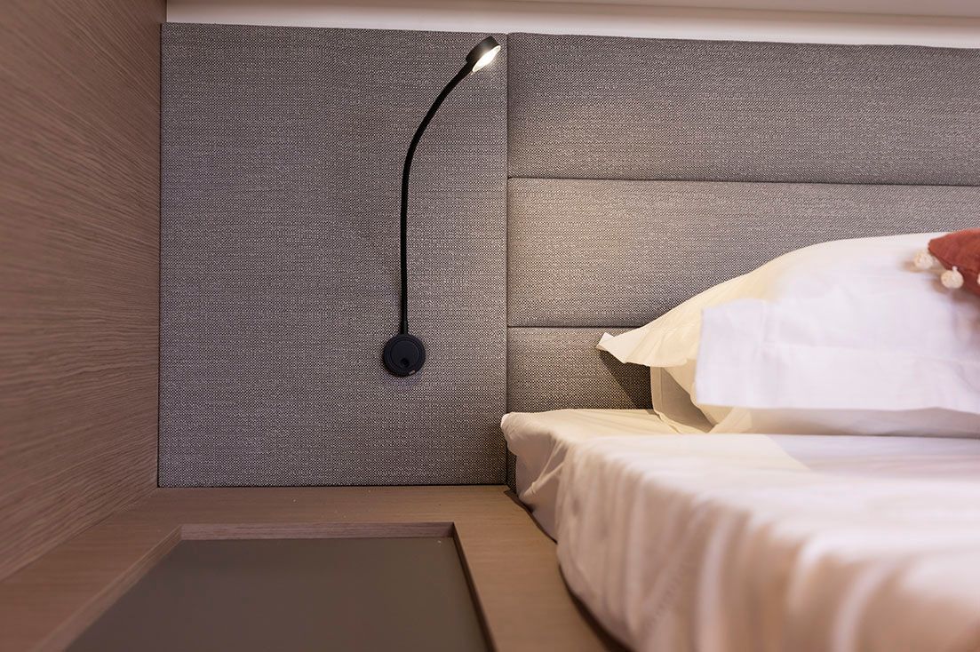 a bedroom with a bed and a lamp on the wall