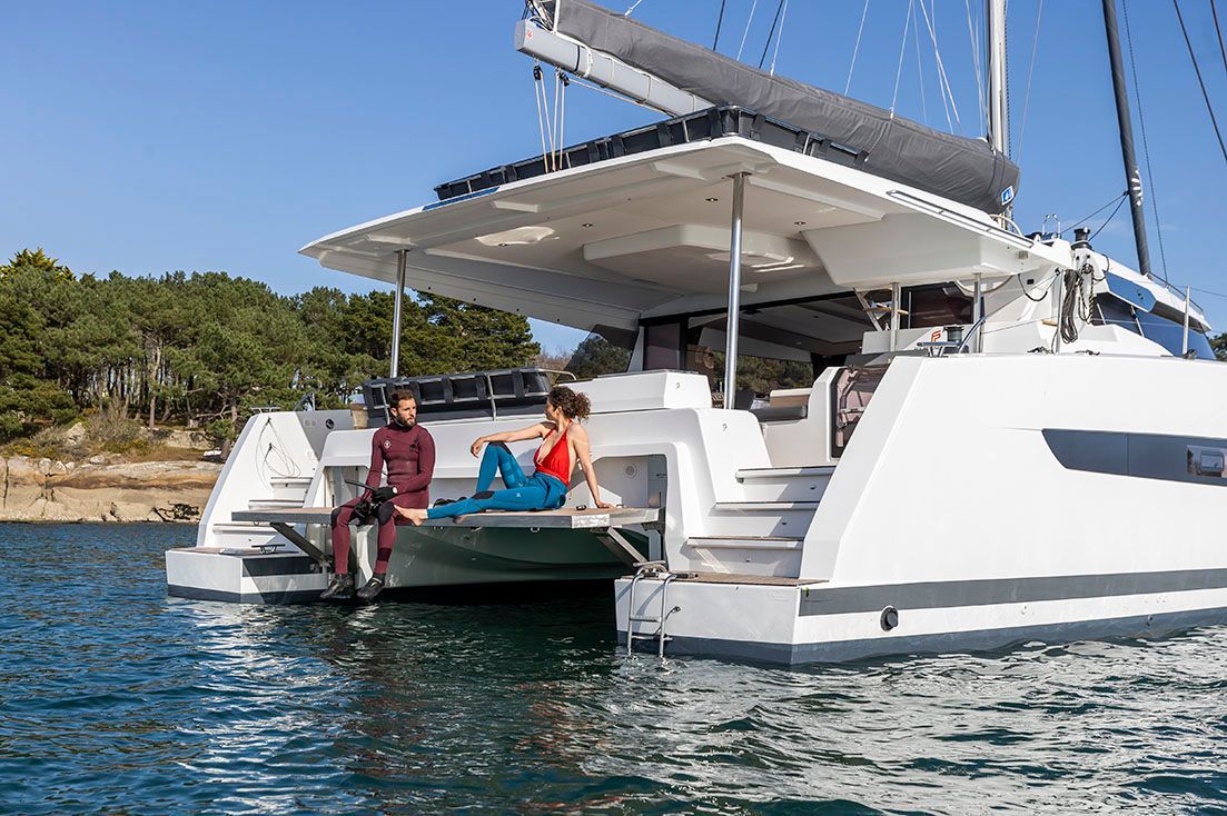 a couple of people are sitting on the back of a sailboat in the water
