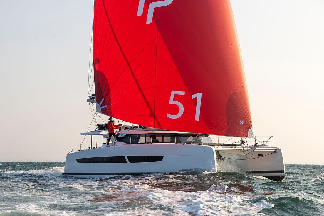 a sailboat with a red sail is floating on top of a body of water