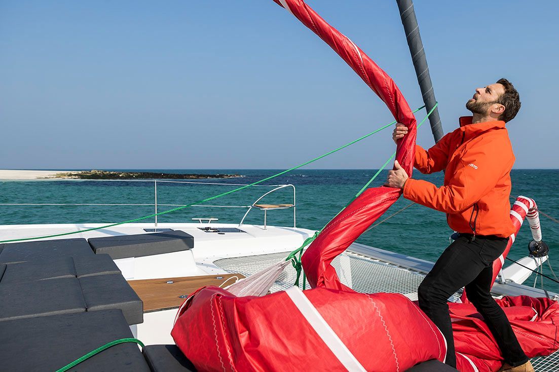 a man is working on a sailboat in the ocean