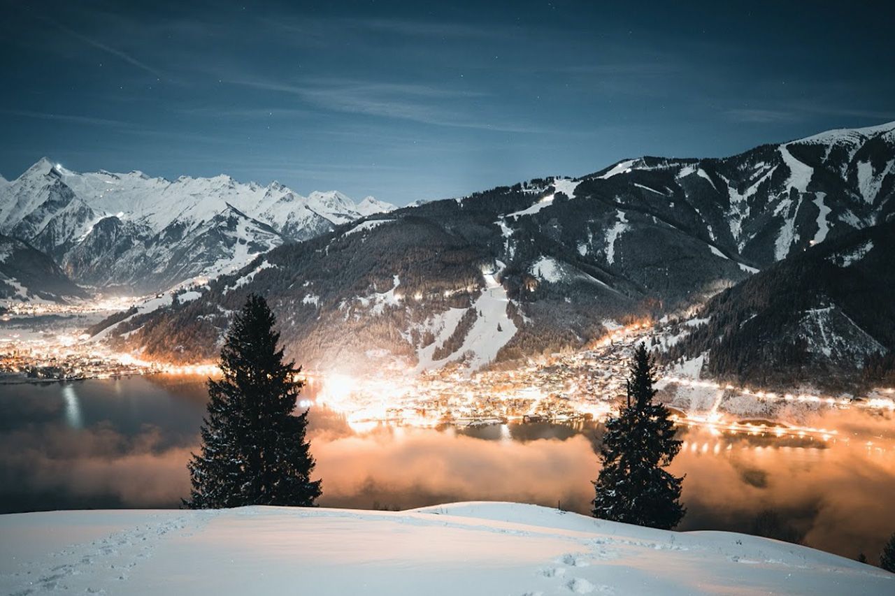 a snowy landscape with a city in the background and mountains in the background