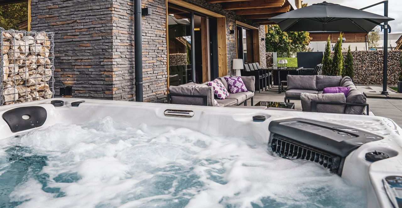 a hot tub is sitting on a patio in front of a house
