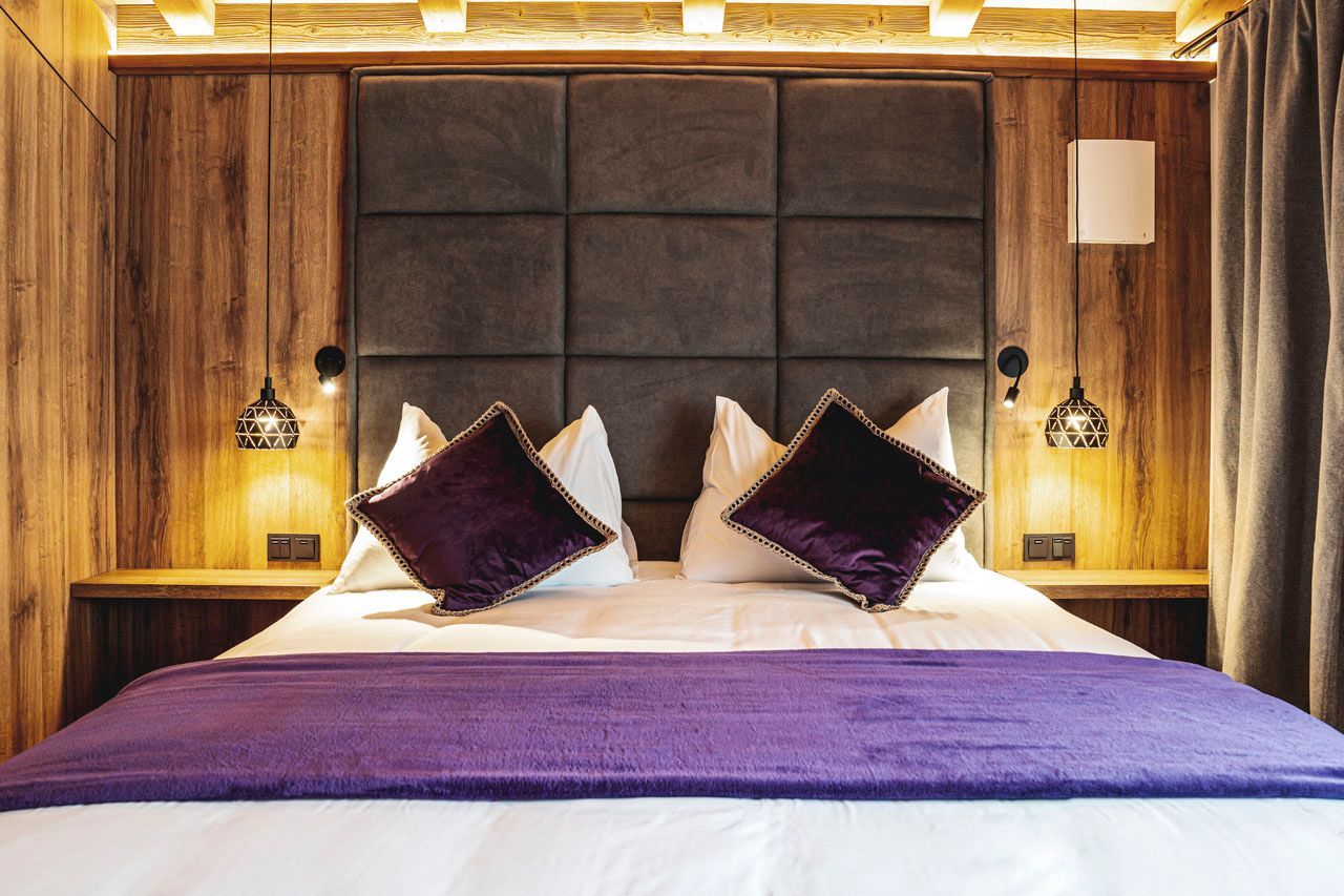 a bed with purple pillows and a purple blanket in a hotel room
