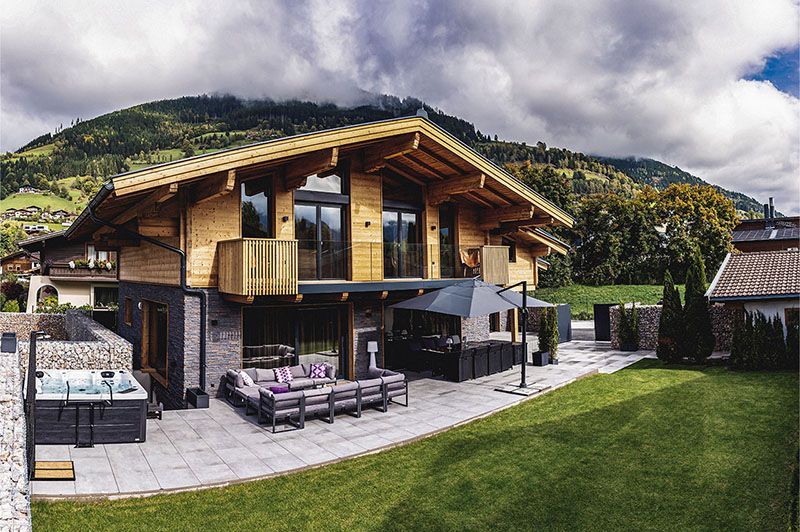 a large wooden chalet with a hot tub in the yard