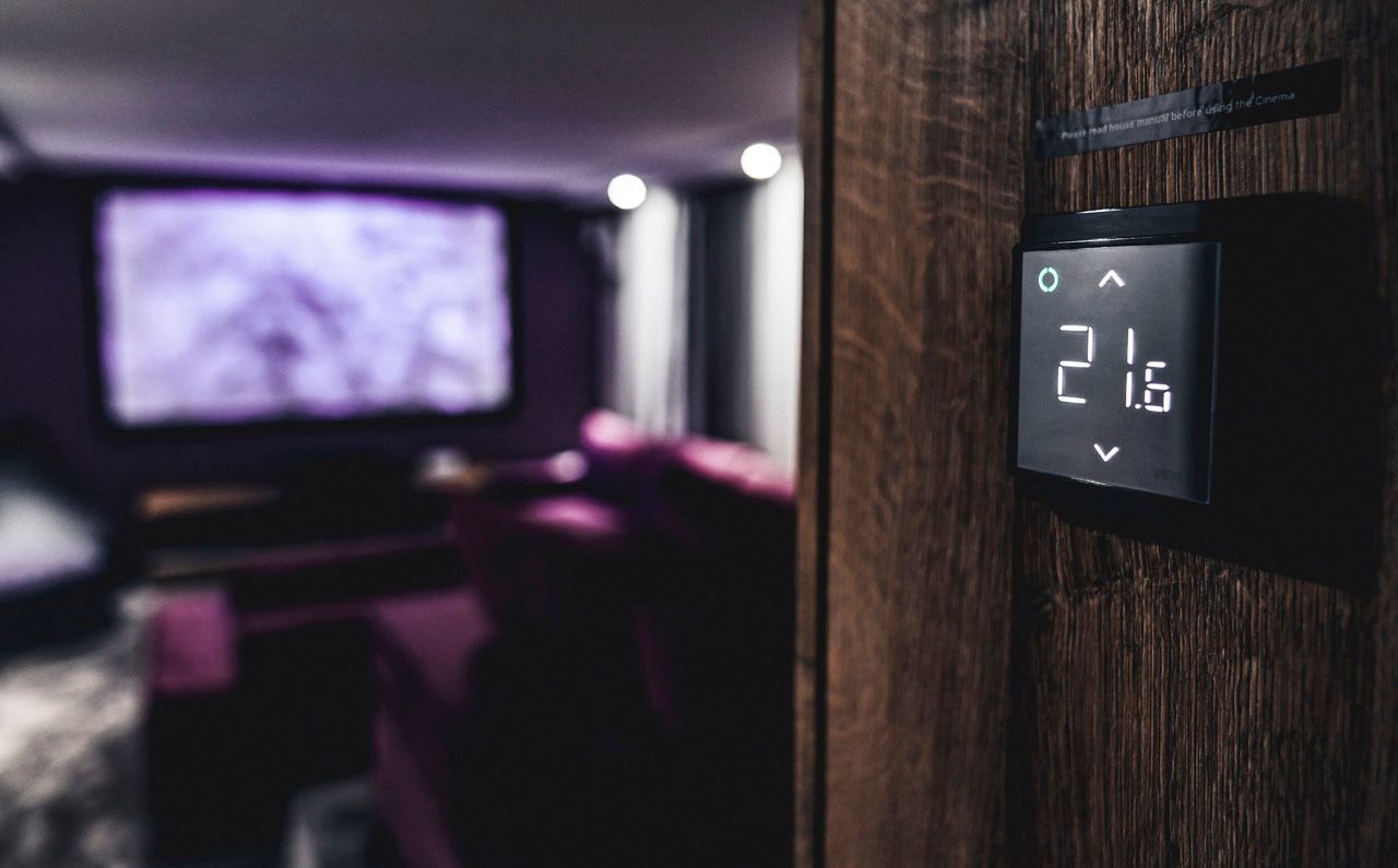 a thermostat is sitting on a wooden wall in a living room
