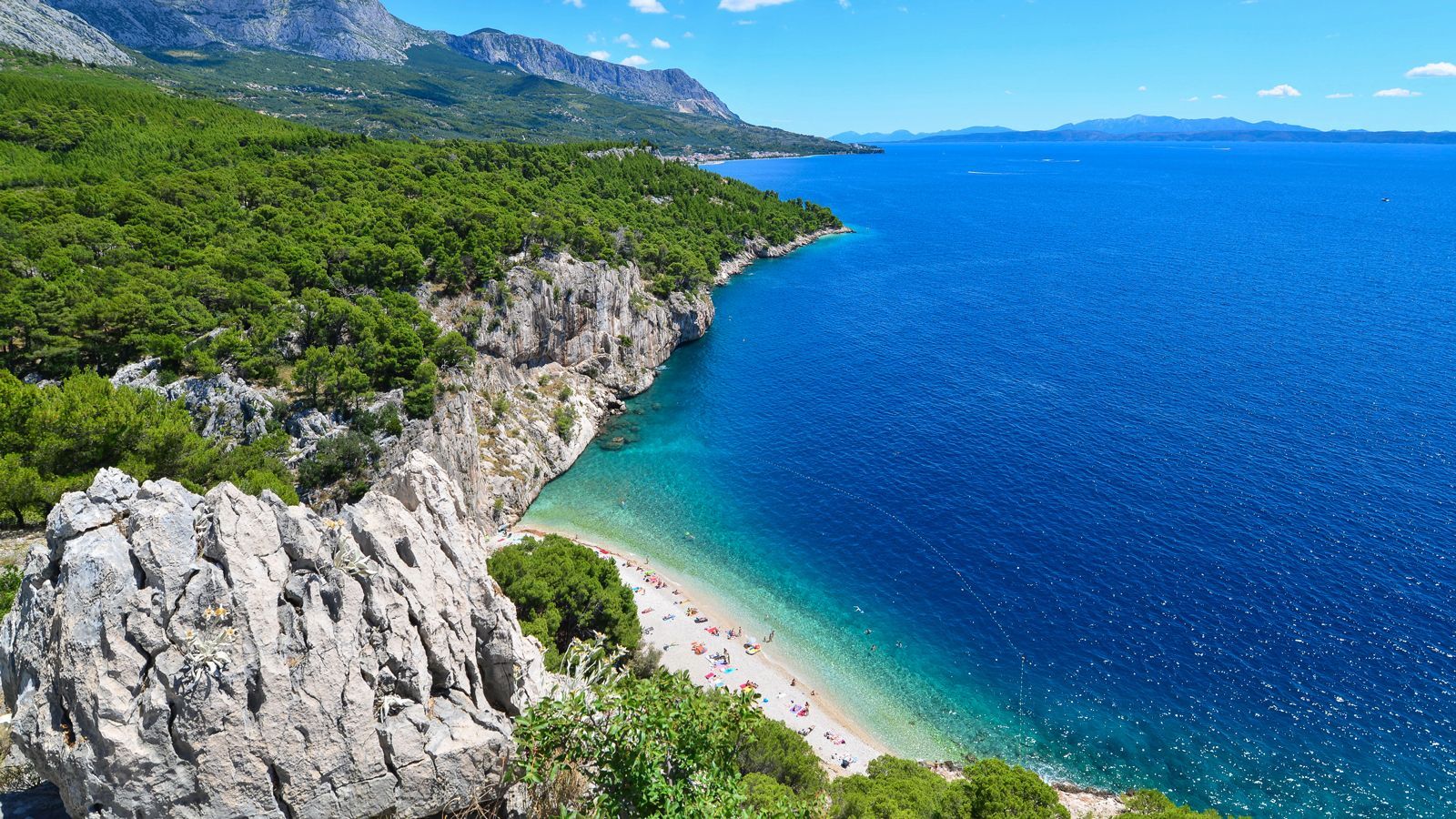 an aerial view of a beach surrounded by mountains and trees